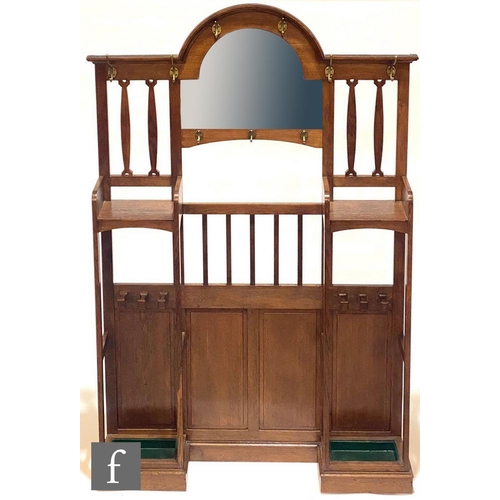 43 - In the manner of Liberty & Co - An oak hallstand, the central arched mirror flanked by pierced l... 