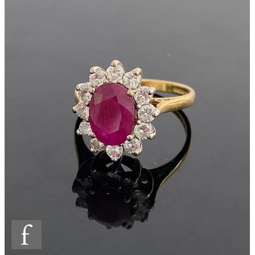 545 - An 18ct hallmarked ruby and diamond cluster ring, central oval ruby, length 10mm, within a border of... 