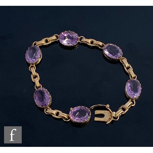 550 - A 9ct hallmarked six stone amethyst bracelet, claw set stones united by fancy belcher links and term... 