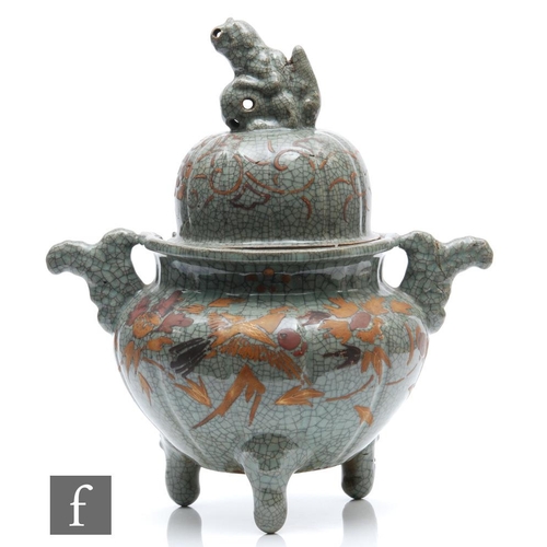 229 - A Chinese Guan type celadon censer raised on tripod supports, applied with relief moulded handles an... 