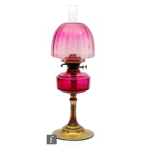 327 - A late 19th Century oil lamp, the brass spreading circular base supporting a faceted cranberry glass... 