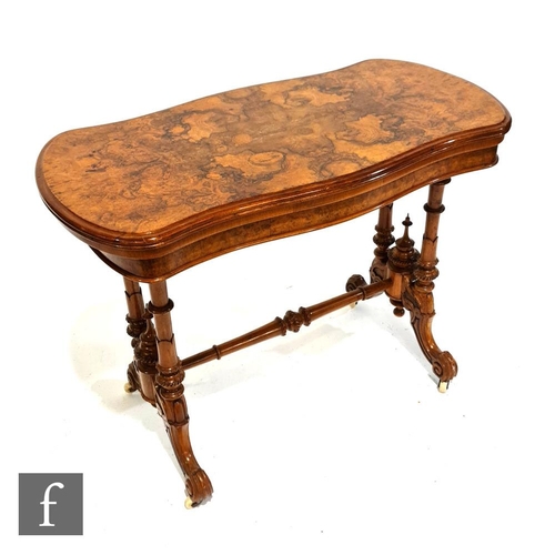 1131 - A Victorian burr walnut veneered fold-over card table of serpentine outline, raised to four turned s... 