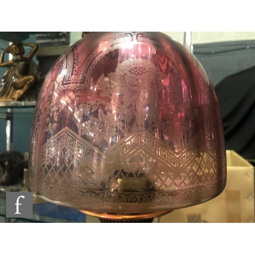 327 - A late 19th Century oil lamp, the brass spreading circular base supporting a faceted cranberry glass... 