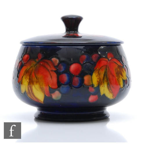 143 - William Moorcroft - A small bowl and cover decorated in the Flambe Leaf and Berry pattern, impressed... 