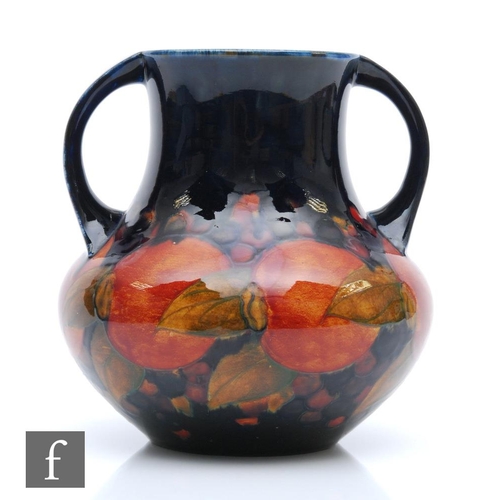 159 - William Moorcroft - A twin handled vase decorated in the Pomegranate pattern with a band of whole fr... 