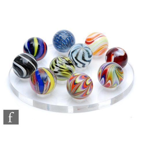 840 - Unknown - Ten assorted hand blown American glass marbles sat on a Perspex circular stand, marble dia... 