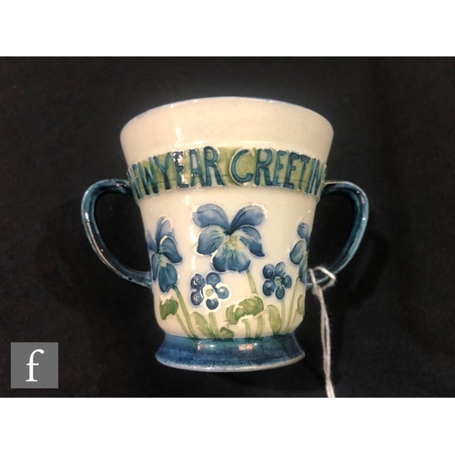 158 - William Moorcroft - James Macintyre & Co - A small twin handled loving cup decorated with blue p... 