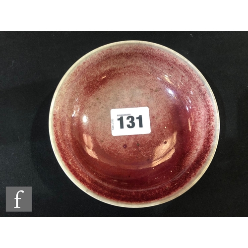 131 - Ruskin Pottery - A small high fired shallow footed bowl decorated in a sang de beouf glaze, impresse... 