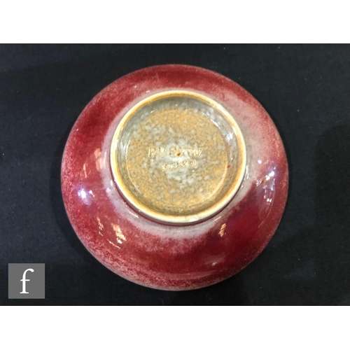 131 - Ruskin Pottery - A small high fired shallow footed bowl decorated in a sang de beouf glaze, impresse... 