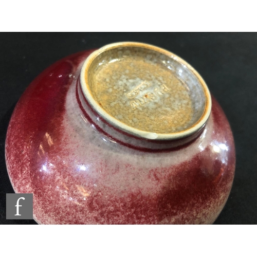 131 - Ruskin Pottery - A small high fired shallow footed bowl decorated in a sang de beouf glaze, impresse... 