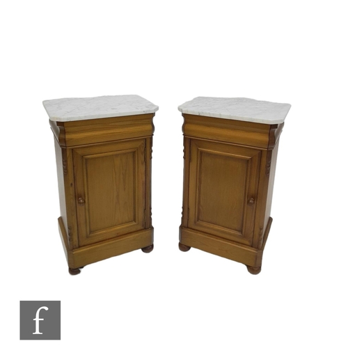 1311 - A pair of Biedermeier style stained pine bedside cupboards, the white marble top over a recessed doo... 