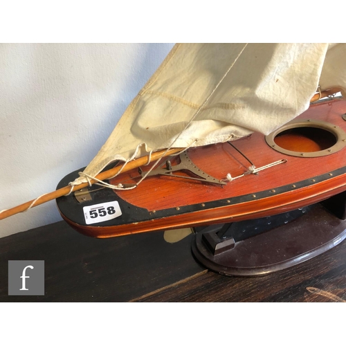 558 - A 1940s or later model pond yacht on wooden stand with beam, length 74cm, a similar single masted ya... 