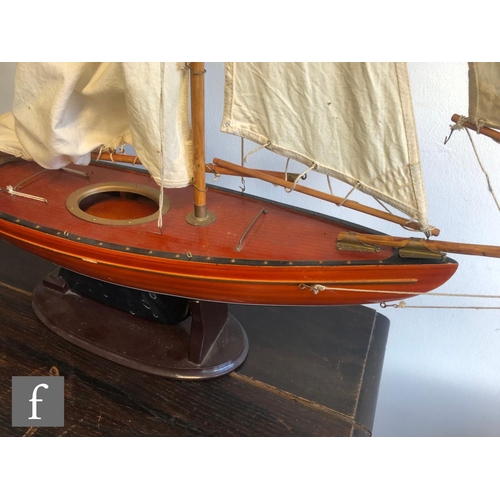 558 - A 1940s or later model pond yacht on wooden stand with beam, length 74cm, a similar single masted ya... 