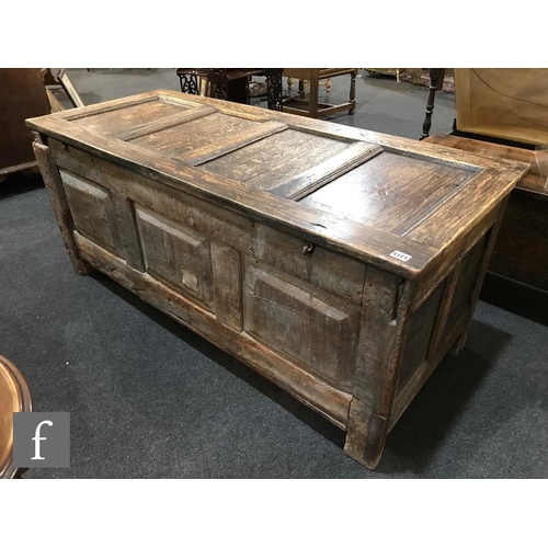 1313 - An 18th Century oak triple panelled coffer, the conforming front below a lunette style frieze on sti... 