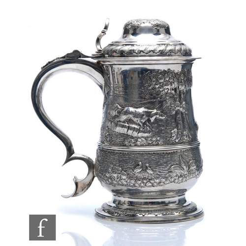 127 - A Georgian hallmarked silver tankard and hinged cover, later embossed with a landscape setting with ... 