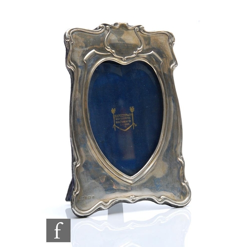 140 - An early 20th Century hallmarked silver easel photograph frame with heart shaped aperture below vaca... 