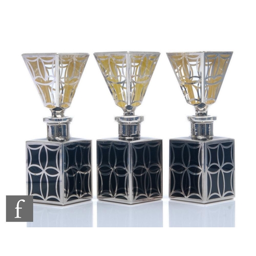 156 - A set of three silver overlaid square sectioned scent bottles each with a black glass body below a t... 