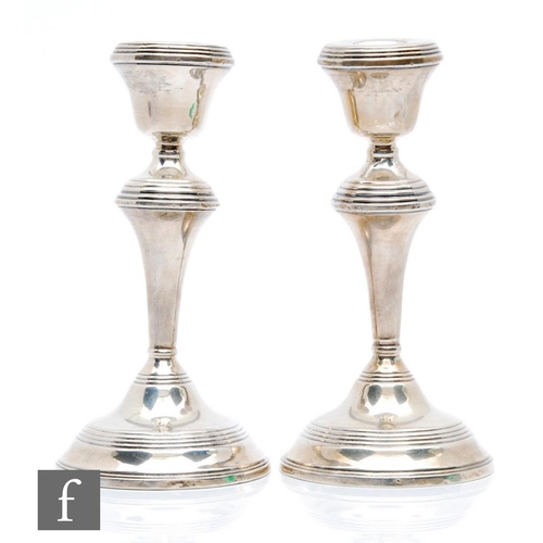 26 - A pair of hallmarked silver candlesticks, each with reeded decoration to circular bases, knops and s... 