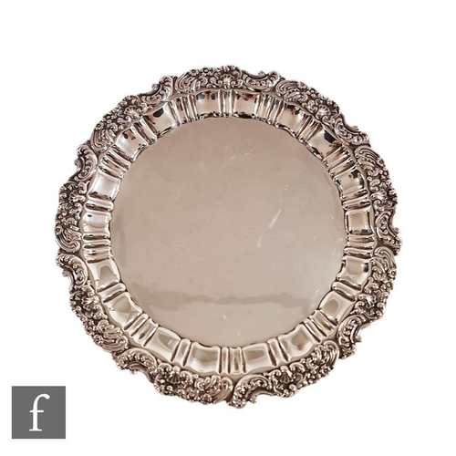 27 - A hallmarked silver circular salver raised on three scroll feet and terminating on pie crust and fol... 