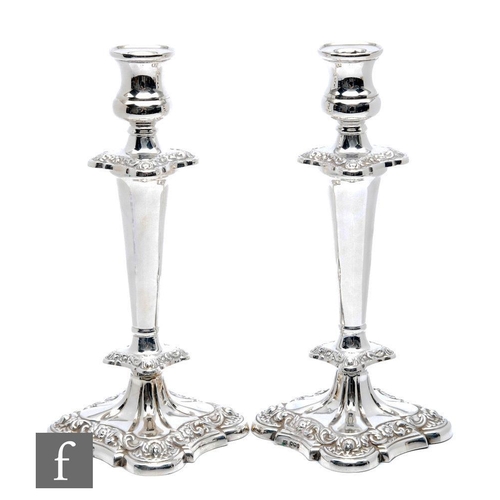 32 - A pair of hallmarked silver candlesticks, foliate embossed shaped square bases below lower knop, pla... 