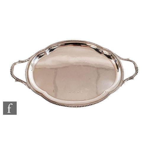 39 - A hallmarked silver twin handled shaped oval tray of plain form terminating in gadroon decorated bor... 