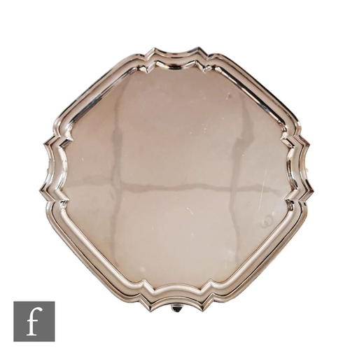 54 - A hallmarked silver canted square salver of plain form with stepped border and raised on four strut ... 