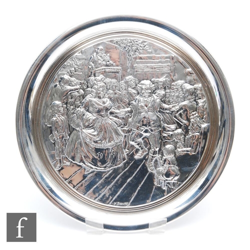 60 - A hallmarked silver Christmas plate embossed with a Dickens' scene within plain raised borders, weig... 