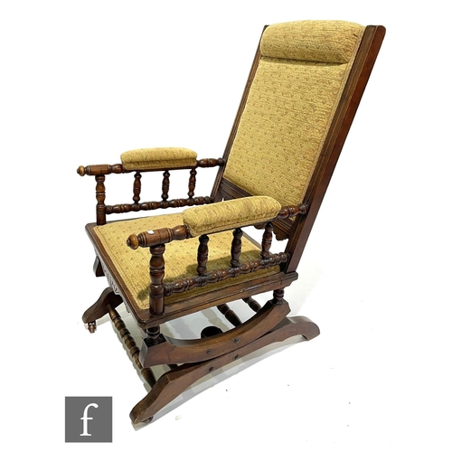 1042 - An American walnut rocking chair upholstered in pale floral design.