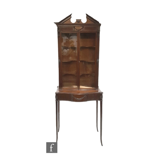 983 - A small Edwardian mahogany Adam style display cabinet enclosed by a pair of glazed doors over a serp... 