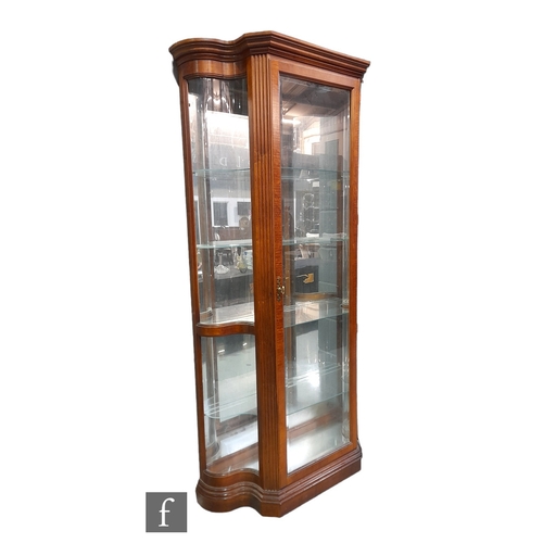 991 - A late 20th Century walnut finish floorstanding serpentine glazed display cabinet enclosed by a sing... 