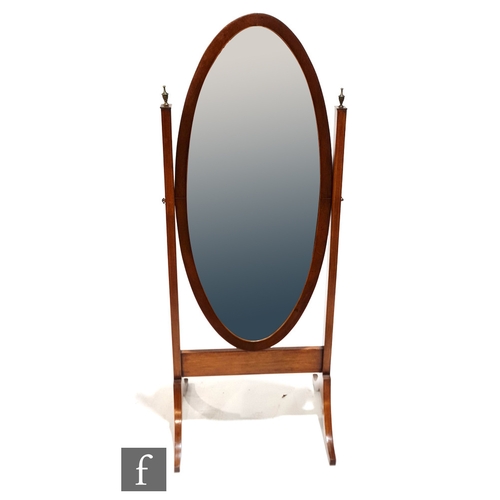 1005 - An Edwardian inlaid mahogany oval cheval mirror supported by two brass final uprights, on splayed le... 