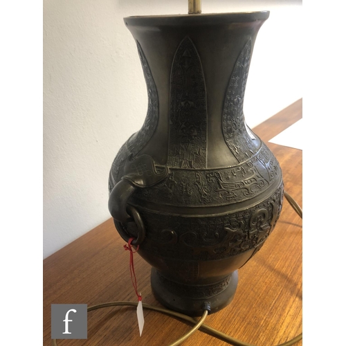 141 - A Chinese cast metal archaic vase, Hu, rising from a high footring and applied with two loop and rin... 