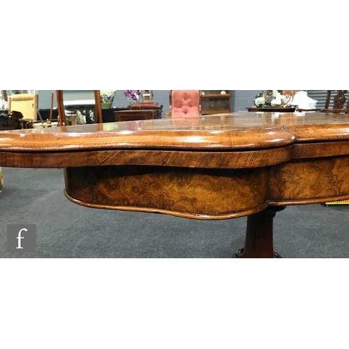 1044 - A Victorian figured walnut veneered fold-over card table of serpentine outline, raised to a turned s... 