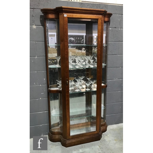 991 - A late 20th Century walnut finish floorstanding serpentine glazed display cabinet enclosed by a sing... 