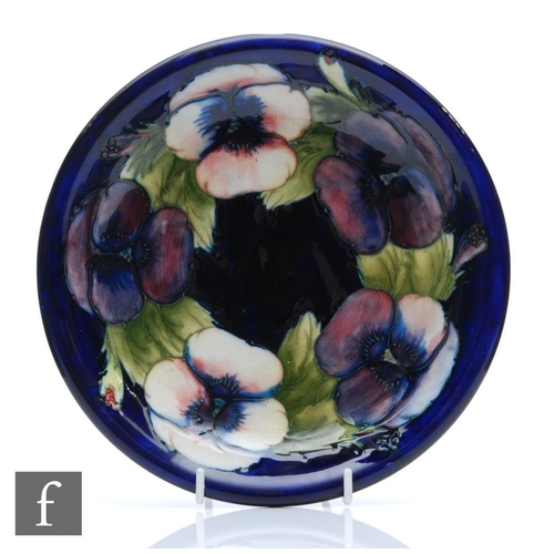 183 - William Moorcroft - A shallow plate with a flared rim decorated in the Pansy pattern, Moorcroft Muse... 