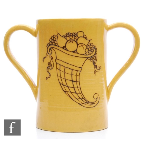 205 - William Moorcroft - A twin handled loving cup decorated with a tubelined cornucopia in brown against... 