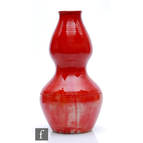 211 - William Moorcroft - A large Natural Pottery vase of gourd form decorated in a translucent red glaze ... 