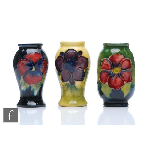 259 - Walter Moorcroft - Moorcroft Pottery - Three miniature vases comprising one in the Pansy pattern, on... 