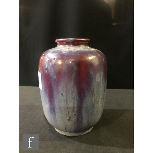 81 - Ruskin Pottery - A small high fired vase of barrel form with a roll rim neck decorated with a lavend... 