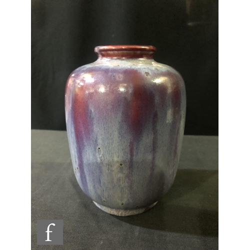 81 - Ruskin Pottery - A small high fired vase of barrel form with a roll rim neck decorated with a lavend... 