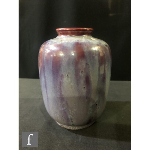 81 - Ruskin Pottery - A small high fired vase of barrel form with a roll rim neck decorated with a lavend... 