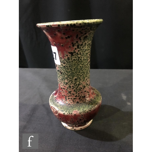 127 - Ruskin Pottery - A small high fired vase of globe and shaft form decorated in a sang de beouf glaze ... 