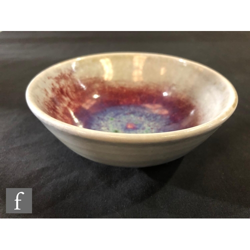 94 - Ruskin Pottery - A high fired bowl with ox blood and lavender pooling to the centre with green spott... 