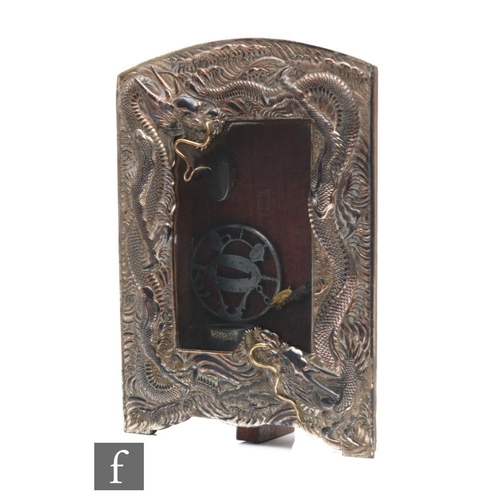 159 - A Japanese sword fitting framed montage, the white metal and glazed frame cast with wrythen dragon, ... 