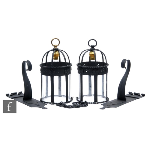 504 - A pair of black painted cylindrical glass hall lanterns each with wall hanging brackets in the Arts ... 