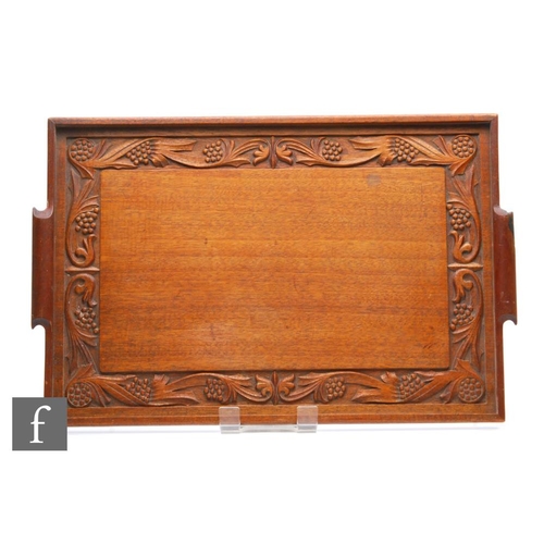 548 - A carved wooden tray in the Arts and Crafts style with a band of stylised leaves and berries, 58cm x... 