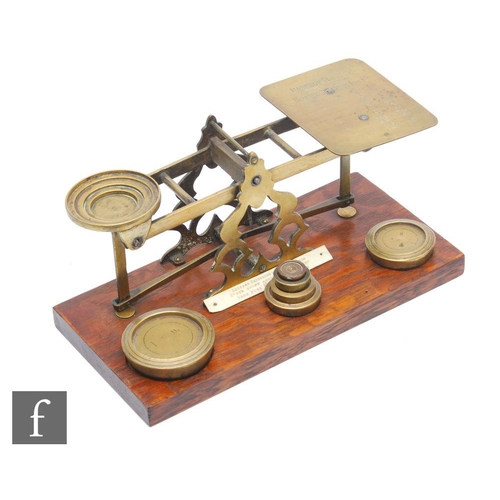 552 - An Edwardian set of brass postal scales and weights, on oak base, width 27cm.