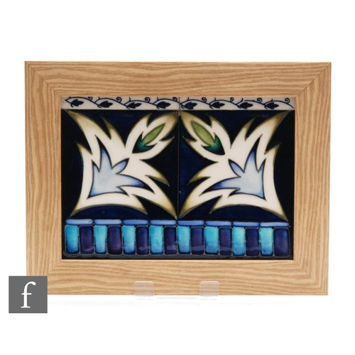 67 - A Moorcroft Pottery framed rectangular panel decorated with two tubelined stylised leaves within pat... 