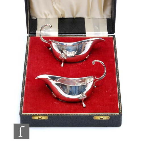 261 - A cased pair of hallmarked silver sauce boats of plain form, total weight 5oz, terminating in flying... 