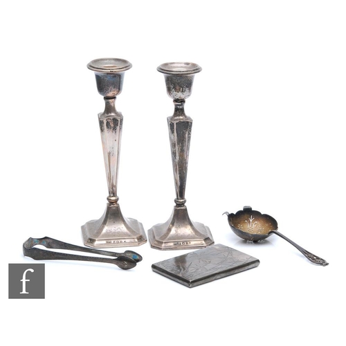 263 - Five items of hallmarked silver to include a pair of candlesticks, a card case, a tea strainer and a... 